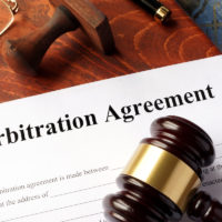 Arbitration agreement form on an office table with gavel hammer and glasses.