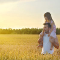 Father takes his daughter in wheat field