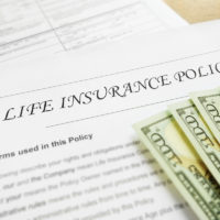 life insurance policy document with hundred dollar bills