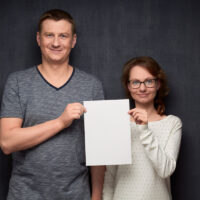 Portrait of couple holding white blank paper sheet together