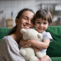 Smiling single young mum embracing little daughter