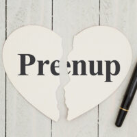 Heart-shape card on weathered wood background with text Prenup