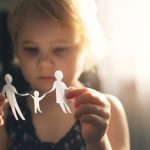 little girl with paper family in hands. concept of divorce, custody and child abuse