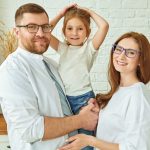 Happy family. Happy father and mother stand in a cozy kitchen holding their daughter in their hands and smiling. Modern interior, furniture for kitchen.