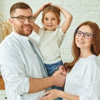 Happy family. Happy father and mother stand in a cozy kitchen holding their daughter in their hands and smiling. Modern interior, furniture for kitchen.