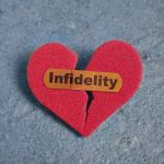 Broken red heart with a bandaid and Infidelity text, on blue