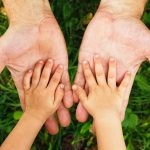 gentle parental hands holding the child's hand