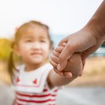 Parent and asian child girl holding hand together with love and care