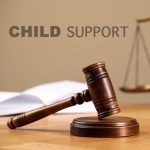 Judge's gavel, scales of justice and book on wooden table. Child support concept