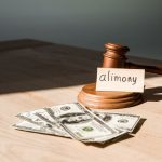 gavel near dollar banknotes and paper with alimony lettering on table