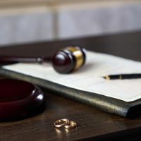Close-up view of a dark brown wooden table with a judge's gavel and sound block, a legal document in a dark-colored folder