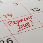 Close Up of a Calendar with Red Payment Due Reminder on White Background