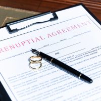 Close-up of a prenuptial agreement form with wedding rings and a fountain pen, indicating the legal aspects of marriage preparation. Close-up of a prenuptial agreement form with wedding rings and a fountain pen, indicating the legal aspects of marriage preparation.