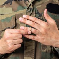 Hands of soldier male who is about to taking off his wedding ring.