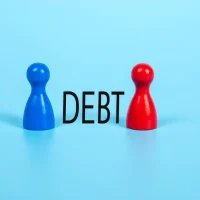 Blue and Red Wooden Board Game Pawns Separated by the Word "DEBT" on a Bright Blue Background Blue and Red Wooden Board Game Pawns Separated by the Word "DEBT" on a Bright Blue Background