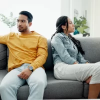 Unhappy, fight and couple angry on a couch together duo to infertility, argument and toxic relationship in a home. Conflict, divorce and man has problem with woman in a living room sofa for cheating