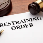 Restraining order legal document on a wooden desk with judge gavel and pen